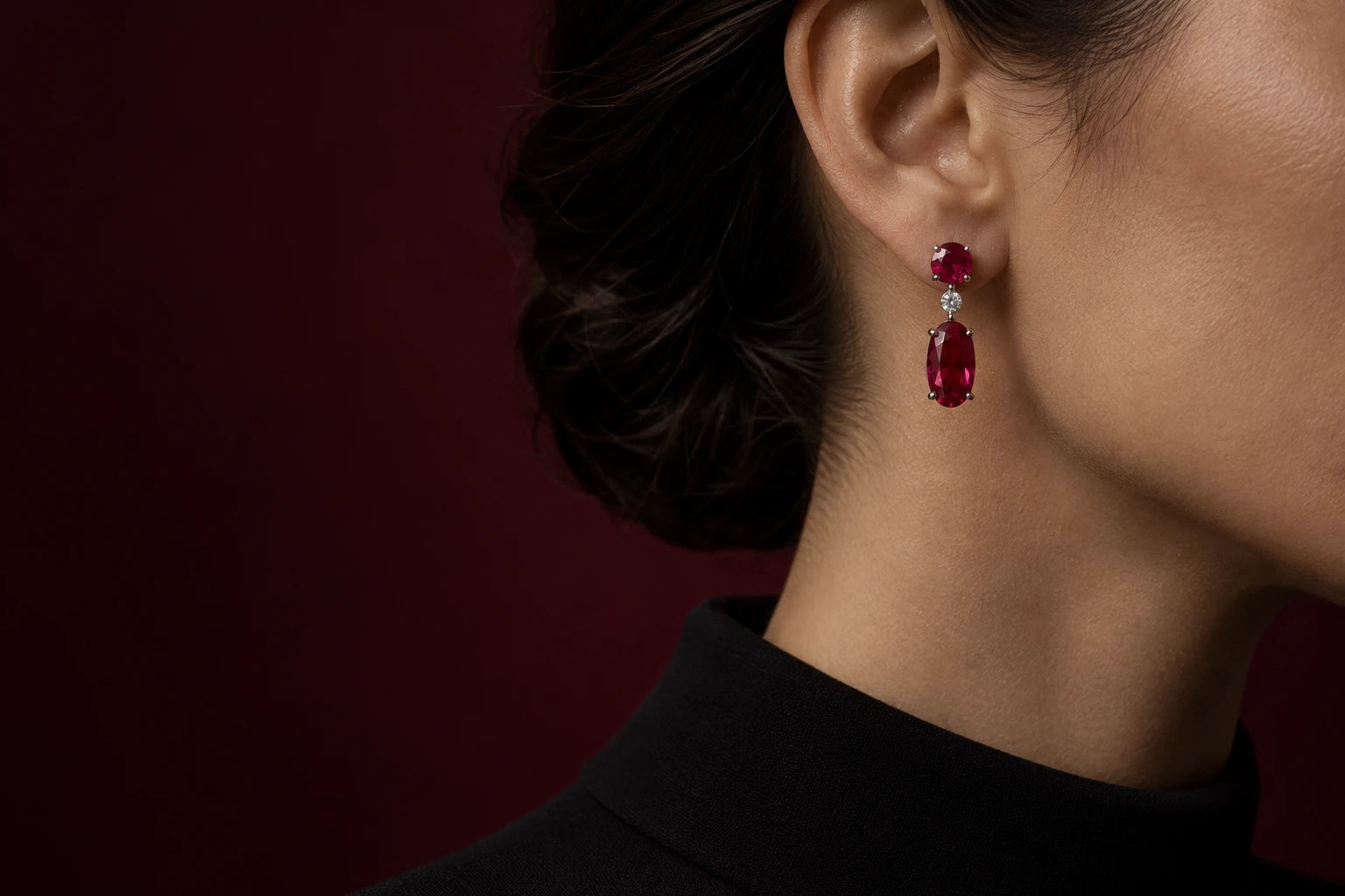 Concept deep-red articulated gemstone earring worn against burgundy